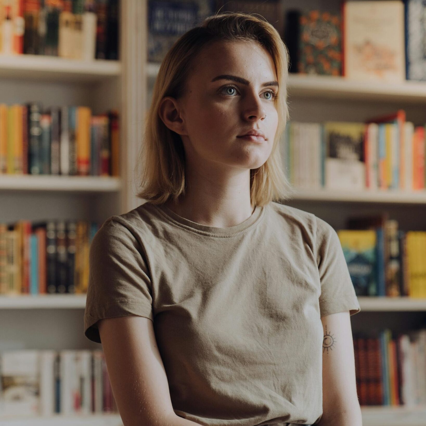 A young woman stands in a bookstore surrounded by colorful bookshelves.